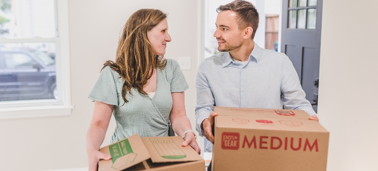 A couple carrying boxes and waiting for long distance movers CT
